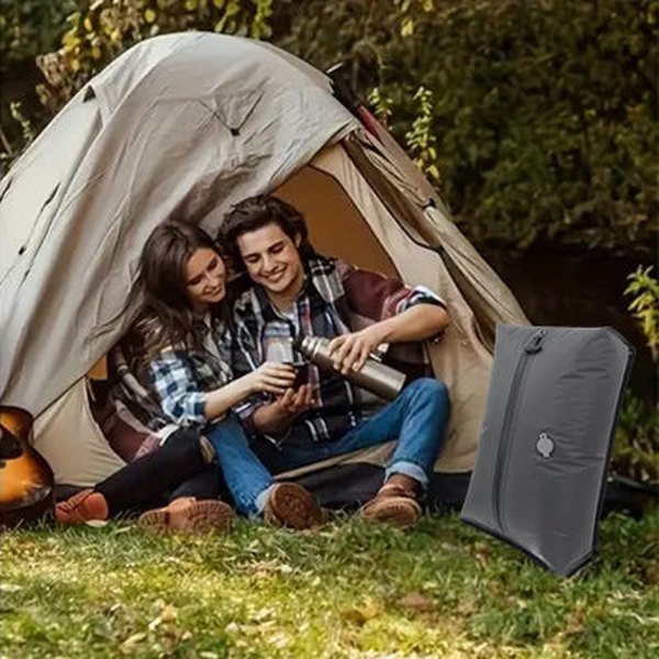 Pareja de acampada con una bolsa de compresión gris junto a la tienda